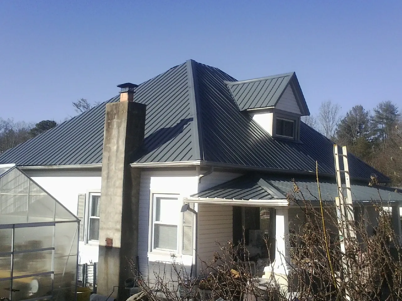 Dark blue standing seam metal roof on a white farmhouse with dormer — Slate & Tile Roof Repair by Roofing Brothers in Dorothy