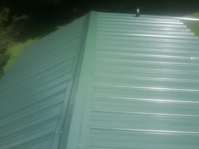 New green metal panels meeting at the ridge of a roof — Flat Roof Repair work by our crew in Dorothy