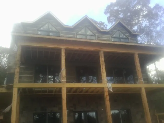 Dormers and porch framing on a large log home under construction — Roof Coating work by our crew in Dorothy