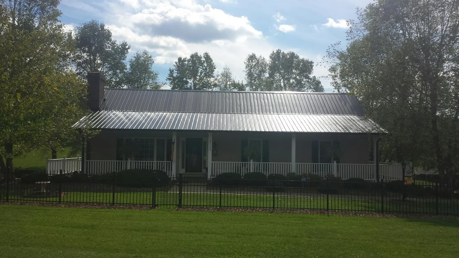 Gray metal roof on a brick ranch with a full width front porch — Gutter Guard Installation work by our crew in Dorothy