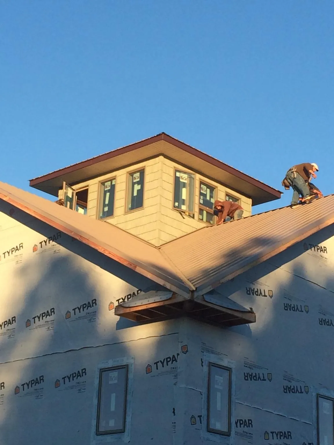 Roofers working around a rooftop cupola on a new metal roof at sunset — Roof Waterproofing in Dorothy by Roofing Brothers